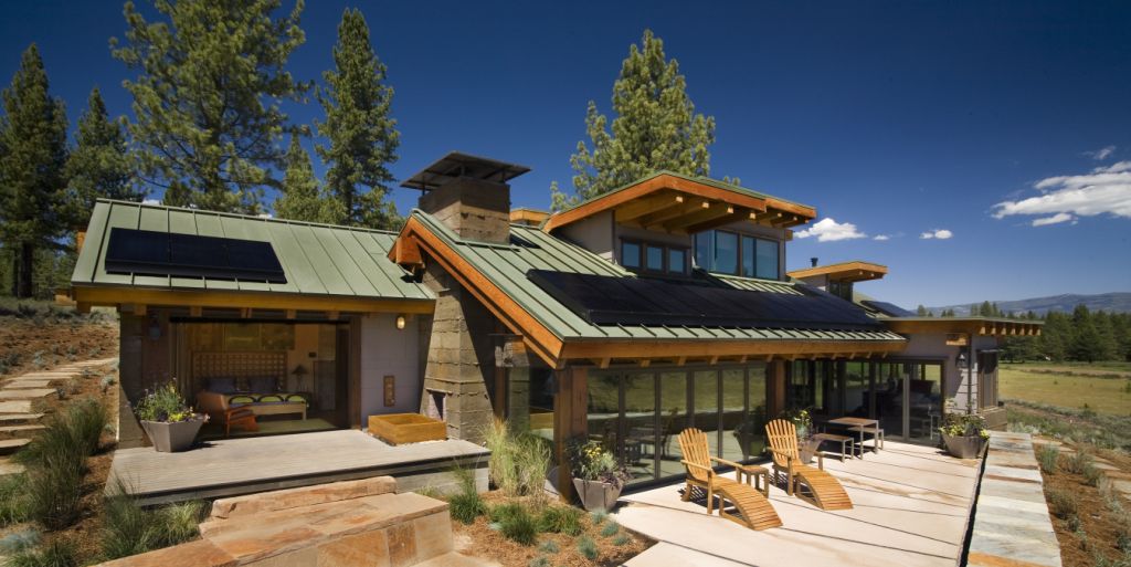 Green roofed home in the mountains with solar panels facing the sun