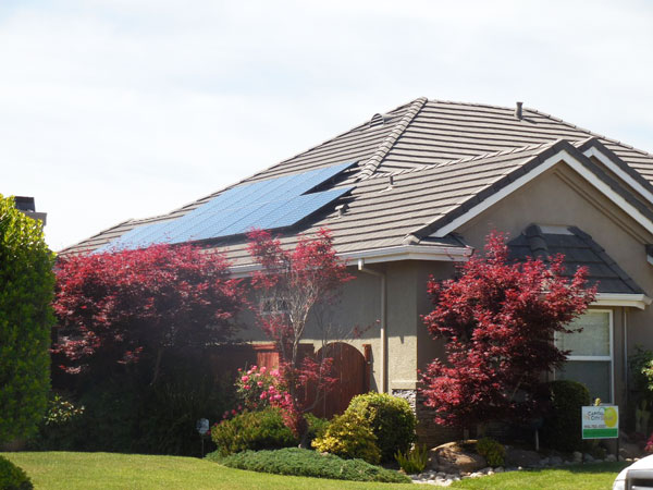 Photo of the side of a house with a large roof and solar panels on the roof