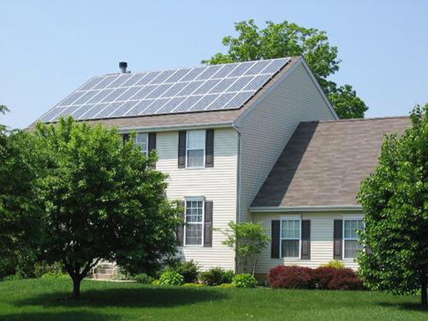 Two story white home with solar panels covering the main structure of the home.