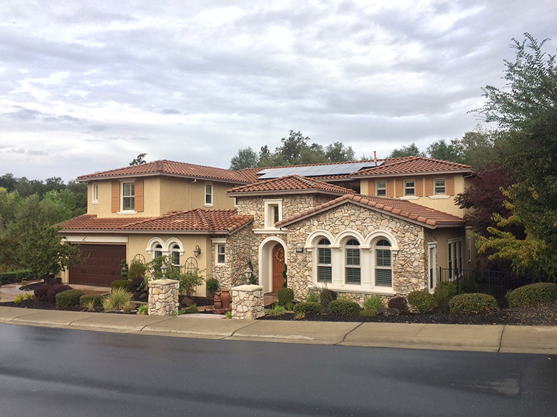Light beige stone home with solar panels on the roof